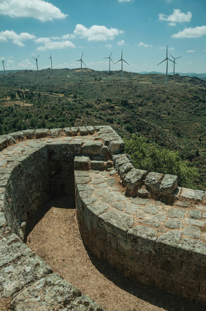 Pathway on thick stone wall with wind turbines over green hilly landscape, in a sunny day at the Sortelha Castle. One of the most astonishing and well preserved medieval villages in all Portugal.のeditorial素材