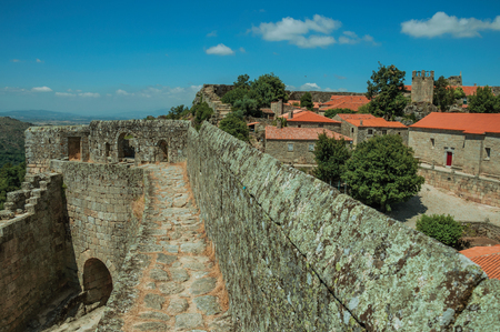 Pathway on thick stone wall with the front gate and green hilly landscape, in a sunny day at the Sortelha Castle. One of the most astonishing and well preserved medieval villages in all Portugal.のeditorial素材