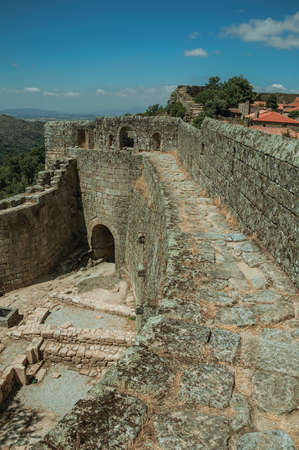 Pathway on thick stone wall with the front gate and green hilly landscape, in a sunny day at the Sortelha Castle. One of the most astonishing and well preserved medieval villages in all Portugal.のeditorial素材