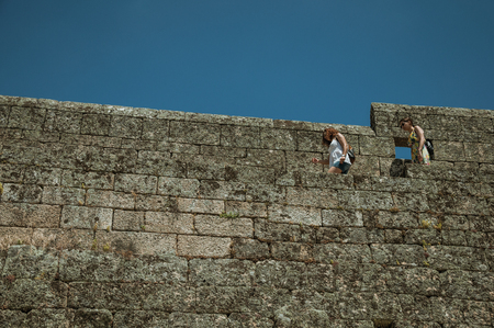 Sortelha, Portugal - July 20, 2018. Women passing through a pathway over large stone wall at the Sortelha Castle. One of the most astonishing and well preserved medieval villages in all Portugal.のeditorial素材