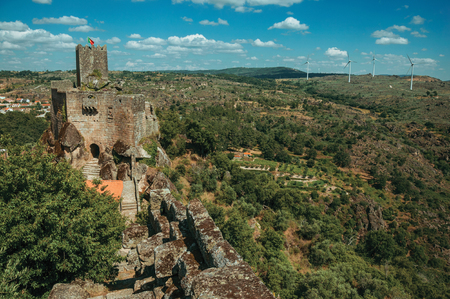 Stone Castle and square tower with flag over rocky cliff on verdant hilly landscape, in a sunny day at Sortelha. One of the most astonishing and well preserved medieval villages in all Portugal.のeditorial素材