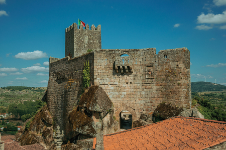 Stone Castle and square tower with flag over rocky cliff on verdant hilly landscape, in a sunny day at Sortelha. One of the most astonishing and well preserved medieval villages in all Portugal.のeditorial素材