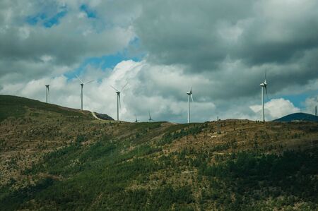 Hilly landscape covered by rocks and several wind generators of electric power, on cloudy day at Serra da Estrela. The highest mountain range in continental Portugal, with astonishing scenery.の写真素材