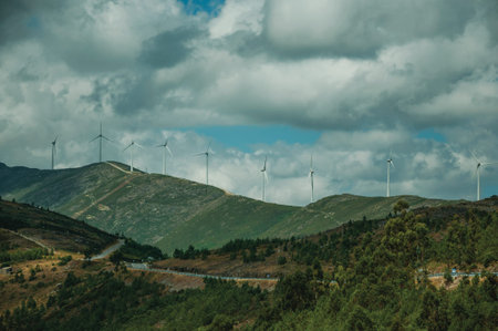 Hilly landscape covered by rocks and several wind generators of electric power, on cloudy day at...