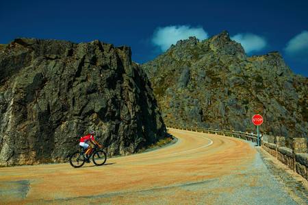 Serra da Estrela, Portugal - July 14, 2018. Curve on roadway passing through rocky landscape with cyclist, at the highlands of Serra da Estrela. The highest mountain range in continental Portugal.のeditorial素材