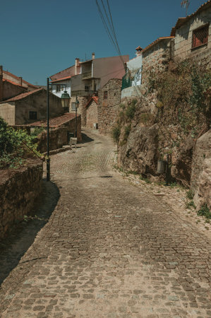 Narrow deserted alley and charming old houses facades with rough stone walls, in a sunny day at Belmonte. A cute small town, birthplace of the navigator Pedro Alvares Cabral, on eastern Portugal.の写真素材