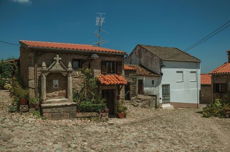 Deserted alley and charming old small house with stone niche for saints, in a sunny day at Belmonte. A cute small town, birthplace of the navigator Pedro Alvares Cabral, on eastern Portugal.の写真素材