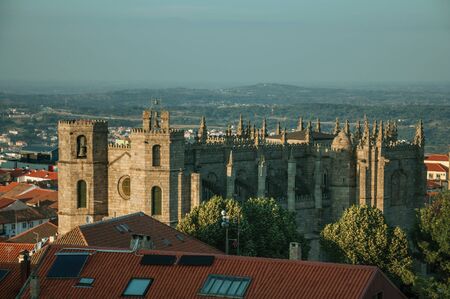 Urban landscape with rooftops of old houses on sunset and gothic facade with steeples at the Guarda Cathedral. This friendly and well-kept medieval town is the highest in the continental Portugal.の写真素材