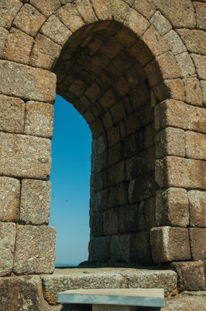 Arched gateway on stone wall over rocky hill, in a sunny day at the Linhares da Beira Castle. A...