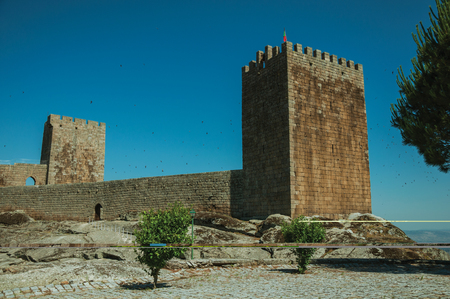 Stone wall with gateway and towers over rocky hill, in a sunny day at the Linhares da Beira Castle. A medieval hamlet with unique architectural diversity fruit of several times, in eastern Portugal.のeditorial素材
