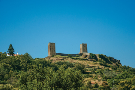 Hilly landscape with trees and rocks in a sunny day and the towers of Linhares da Beira Castle. A medieval hamlet with unique architectural diversity fruit of several times, in eastern Portugal.のeditorial素材
