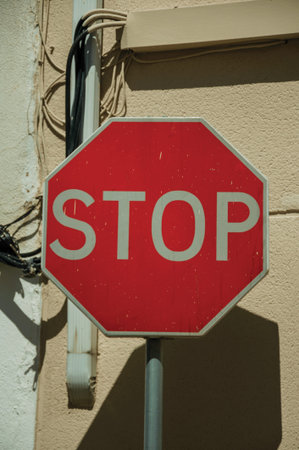 Close-up of NO ENTRY road sign in front of beige and white rough plaster wall, in a sunny day at...