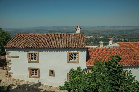 Charming facade of old house with whitewashed wall in cobblestone alley on the way down, in a sunny day at Marvao. An amazing medieval fortified village perched on a granite crag in eastern Portugal.の写真素材
