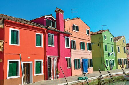 Panoramic view of colorful buildings and boats in front of a canal, in a sunny day at Burano, a gracious little town full of canals, near Venice. Located in the Veneto region, northern Italyの写真素材