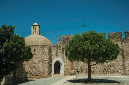 Elvas, Portugal - July 07, 2018. Stone wall with door and small tree on a sunny day, in front of the Elvas Castle. A gracious star-shaped fortress city on the easternmost frontier of Portugal.のeditorial素材