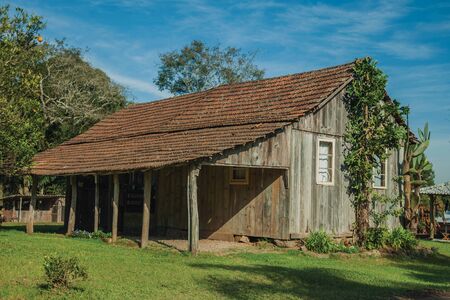 Facade of an old charming shack made of wood in a traditional rural style with lush vegetation, near Bento Goncalves. A friendly country town in southern Brazil famous for its wine production.の写真素材