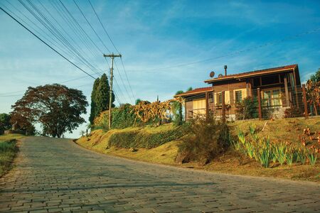 Charming countryside wood house with garden next to a stone paved road at sunset, near Bento Goncalves. A friendly country town in southern Brazil famous for its wine production.の写真素材