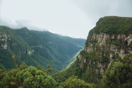 Fortaleza Canyon with steep rocky cliffs covered by thick forest and fog coming up the ravine near Cambara do Sul. A small country town in southern Brazil with amazing natural tourist attractions.の写真素材