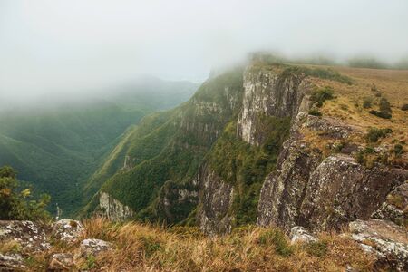 Fortaleza Canyon with steep rocky cliffs covered by thick forest and fog coming up the ravine near Cambara do Sul. A small country town in southern Brazil with amazing natural tourist attractions.の写真素材