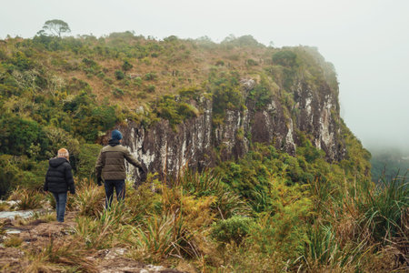 People on edge of cliff and mist coming up from the green valley at Serra Geral National Park near Cambara do Sul. A small rural town in southern Brazil with amazing natural tourist attractions.の写真素材