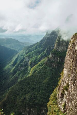 Huge Fortaleza Canyon with steep rocky cliffs covered by thick forest in a cloudy day near Cambara do Sul. A small country town in southern Brazil with amazing natural tourist attractions.の写真素材