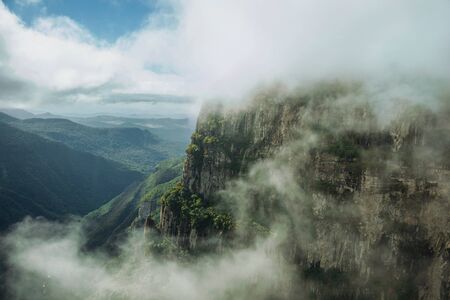 Fortaleza Canyon with steep rocky cliffs covered by thick forest and fog coming up the ravine near Cambara do Sul. A small country town in southern Brazil with amazing natural tourist attractions.の写真素材