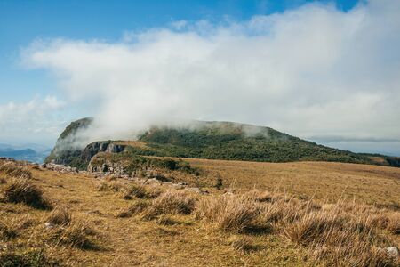 Summit of highest cliff at Fortaleza Canyon with rocky landscape covered by dry bushes and clouds near Cambara do Sul. A small country town in southern Brazil with amazing natural tourist attractions.の写真素材