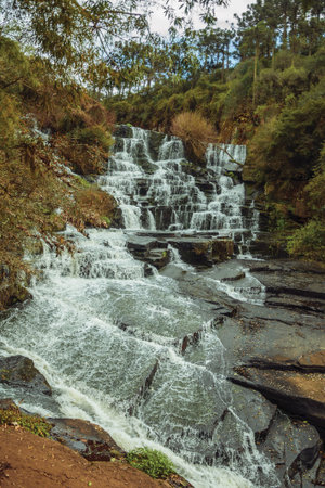 Waterfall falling over rocks amid lush forest in a cloudy day at the Caracol Park near Canela. A charming small town very popular by its ecotourism in southern Brazil.の写真素材