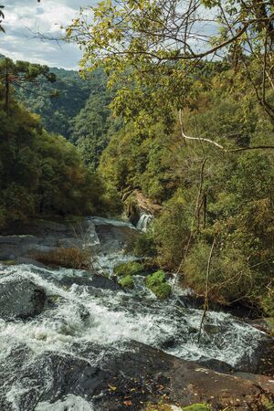 Waterfall falling over rocks amid lush forest in a cloudy day at the Caracol Park near Canela. A charming small town very popular by its ecotourism in southern Brazil.の写真素材