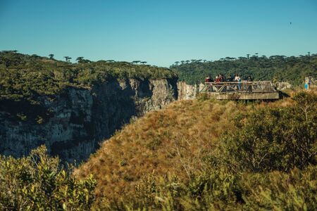 Cambara do Sul, Brazil - July 16, 2019. People at wooden belvedere on the edge of cliff at the Itaimbezinho Canyon near Cambara do Sul. A small country town with amazing natural tourist attractions.の写真素材