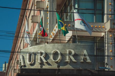 Bento Goncalves, Brazil - July 11, 2019. Company signboard and flags on the facade of Aurora Winery building at Bento Goncalves. A friendly country town famous for its wine production.のeditorial素材