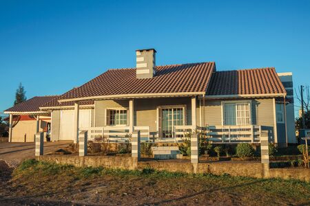 Cambara do Sul, Brazil - July 16, 2019. Charming modern townhouse with fence and garden at sunset, in a dirt street of Cambara do Sul. A small country town with amazing natural tourist attractions.のeditorial素材
