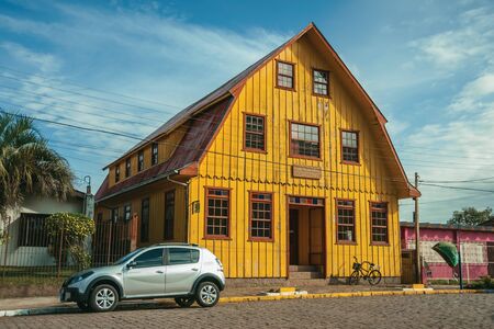 Cambara do Sul, Brazil - July 19, 2019. Facade of wooden old house and parked car in a stone street at Cambara do Sul. A small rural town with amazing natural tourist attractions.のeditorial素材