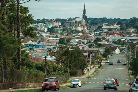 Canela, Brazil - July 21, 2019. Street with cars going towards cityscape of houses and church steeple in Canela. A charming small town very popular by its ecotourism.のeditorial素材