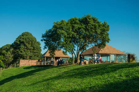 Pardinho, Brazil - June 20, 2019. People taking pictures and having fun on top of hill covered by green lawn in an estate near Pardinho. A small rural village in the countryside of Sao Paulo State.のeditorial素材