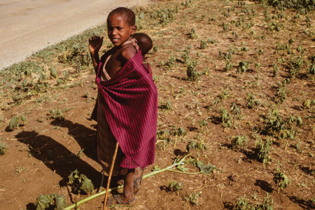 Serengeti, Tanzania - February 10, 1997. Inquisitive Maasai children dressed in typical clothes at Serengeti. A huge national park in the African savanna where several species of large mammals live.のeditorial素材