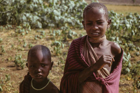 Serengeti, Tanzania - February 10, 1997. Inquisitive Maasai children dressed in typical clothes at Serengeti. A huge national park in the African savanna where several species of large mammals live.のeditorial素材