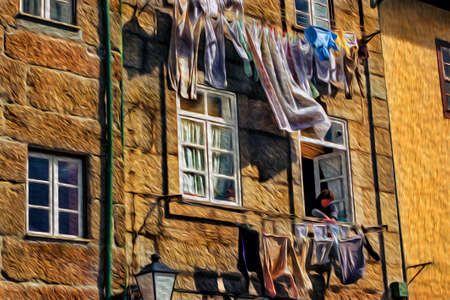 Woman at the window of her house hanging clothes on the clothesline in Lisbon. An old city located along the Douro River estuary and the second-largest city in Portugal. Oil paint filter.の写真素材