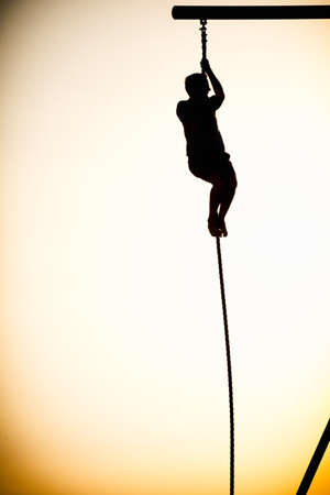 Silhouette of a person climbing a rope on the beach, Santa Monica Beach, Santa Monica, Los Angeles County, California, USAの写真素材