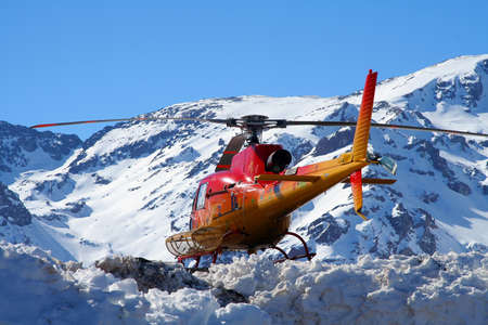 Rescue helicopter flying over snow covered mountain, Santiago, Chileの写真素材