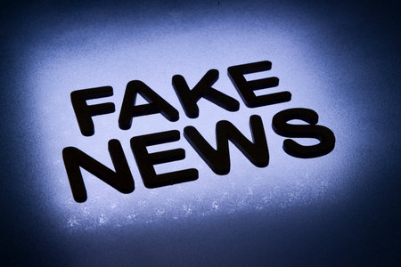 word fake news written in wood letters and lit by background in backlight