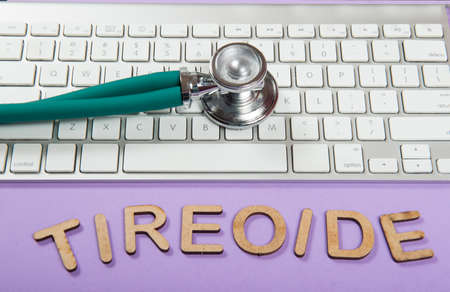 Keyboard and stethoscope on lilac background, with the word thyroid (Tireoide)の写真素材