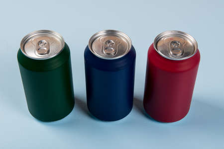 three colored cans of soft drinks closed on a light blue background.の写真素材