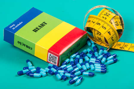 medicine box with some blue capsule and measuring tapeの写真素材