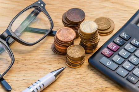 business, finance, money  concepts - calculator, eyeglasses coins on  a office tableの写真素材
