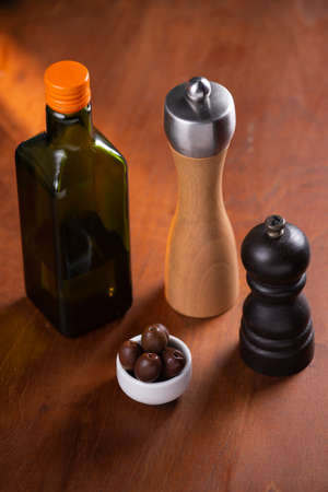 salt shaker, pepper, bottle of olive oil over wooden tableのeditorial素材