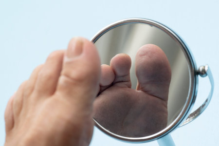 Person looking at the sole of the foot in a mirror, to check if there is no diabetic foot, as possible soresの写真素材