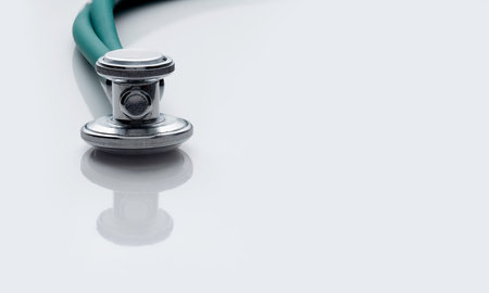 detail of stethoscope on white background, with a blood test tube labeled covid-19 and capsules
