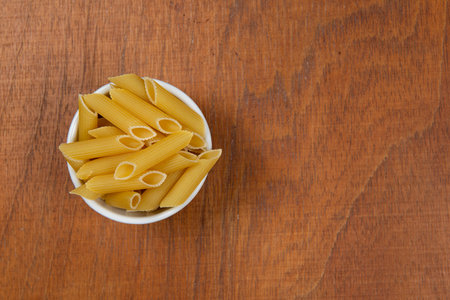 bowl with raw pasta on wooden background. Topview