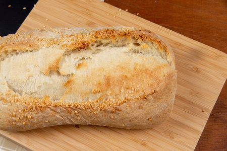 homemade french type bread with sesame on rustic wooden background